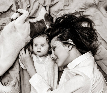 年轻母亲和有狗的小孩躺在床底背景上图像以黑白颜色图片