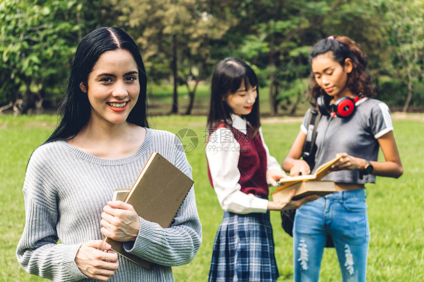 微笑的女国际学生或青少年站着拿书图片