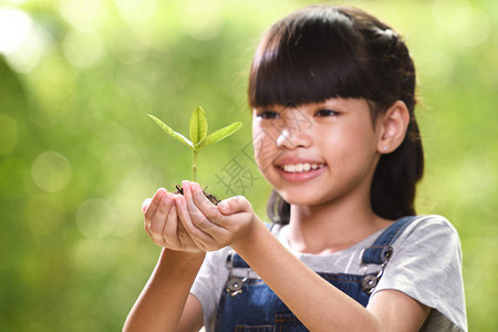 一个女孩手里拿着一株年轻的植物图片