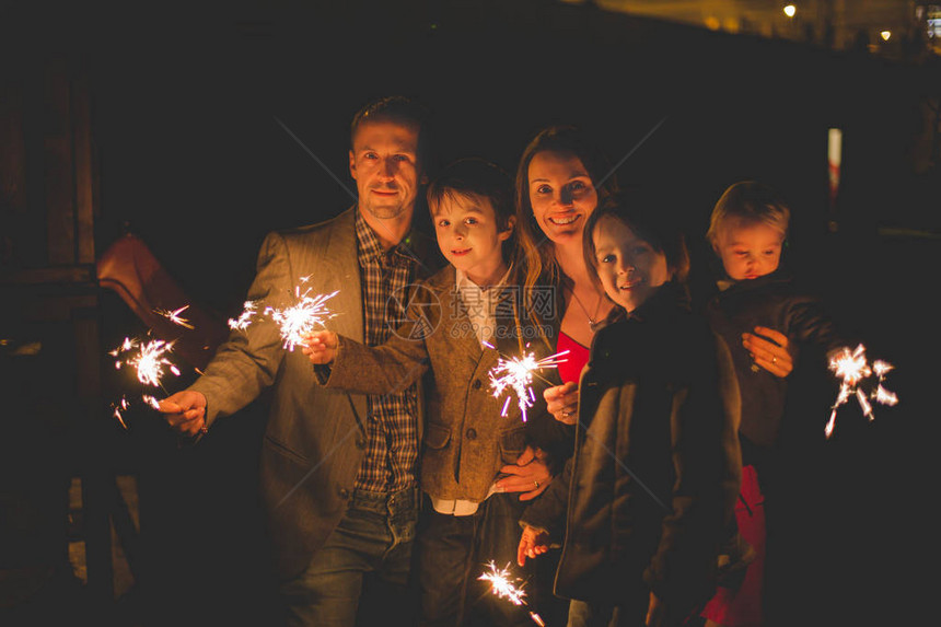 一同庆祝新年的幸福家庭与花园外户照明火花灯光的图片