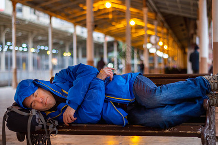 在火车站长凳上睡觉的乘客背景图片