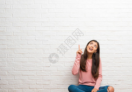 坐在房间地板上的少女打算在举起手指的同时图片