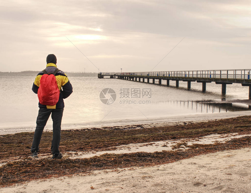 站在海上的后包装旅游者在老木桥上在海图片