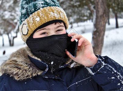 电话男孩在讲话穿着编织的帽子在冬天散步时带着布波图片