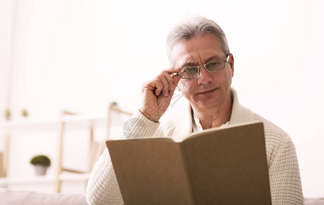 戴眼镜看书的成熟男人在家休息图片