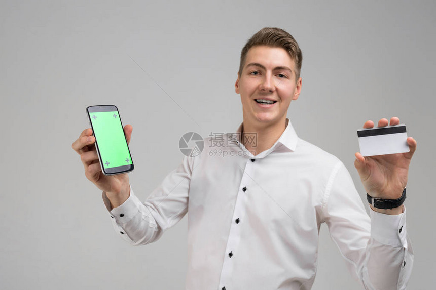 年轻人拿着黑屏手机和显示信用卡被隔离网上银行业务一名男子使用智能手机和信用卡在相机上摆姿势进行网上购图片