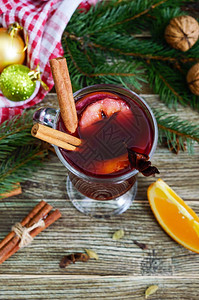 木桌上的玻璃杯里的热甜酒基于葡萄酒果汁香料调味料水果的芳香传统冬图片