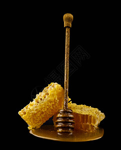 黑色背景中带蜂蜜勺的蜂窝蜜蜂图片