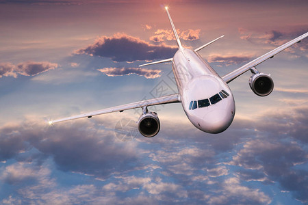 商业飞机喷气机在美丽的夕阳光下飞越云层上空飞图片
