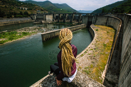 坐在废弃水力发电厂附近的妇女图片