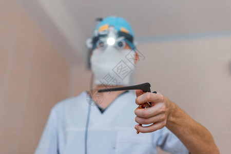 戴着医用口罩身穿白色长袍戴着双筒放大镜的显微外科医生站在手术室里图片