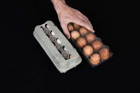 男手挑一个塑料鸡蛋盒而不是一盒装满鸡蛋的盒子在黑图片