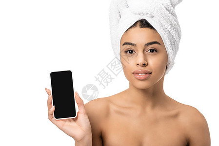 头戴毛巾用空白屏幕拿着智能手机看着白色被孤立的相机的有魅力图片