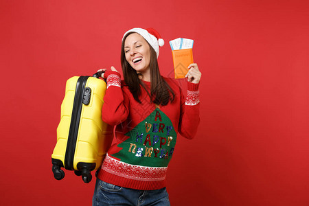 笑着戴圣诞帽的年轻圣诞老人女孩拿着黄色的手提箱背景图片