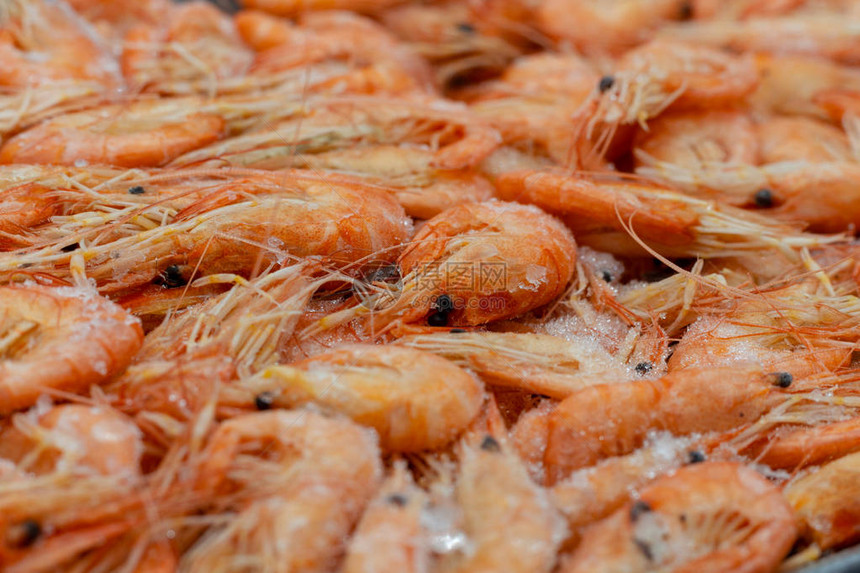 新鲜解冻的美味虾与扭曲的尾巴特写一个柜台的宏观照片与新鲜冷冻的橙色虾海冻虾在白霜图片