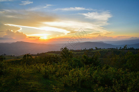 山丘上黄色和蓝色的天空与山地风景的田野日落美景背图片