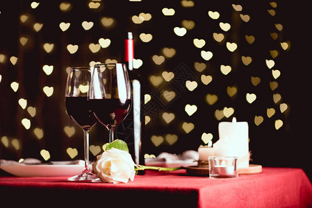 桌边摆着红葡萄酒玫瑰和心形的杯子图片