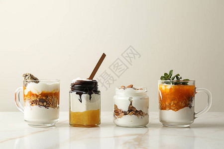 桌上有果酱燕麦片和蜜饯坚果的美味酸奶玻璃器皿图片