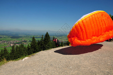 滑翔机准备跳伞用橙色降落伞在山谷上空展图片