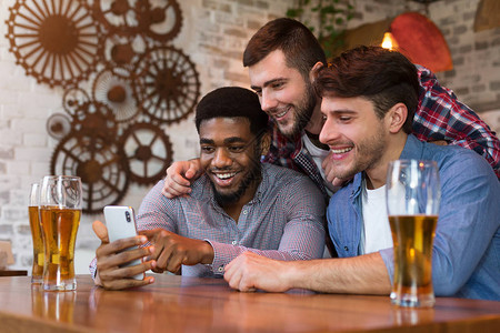 不同朋友在酒吧里观看智能手机和啤酒的视频图片
