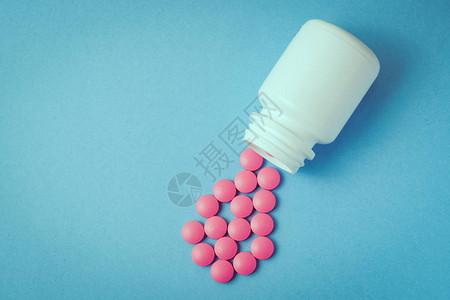 粉色药丸从一个蓝色的白色图片