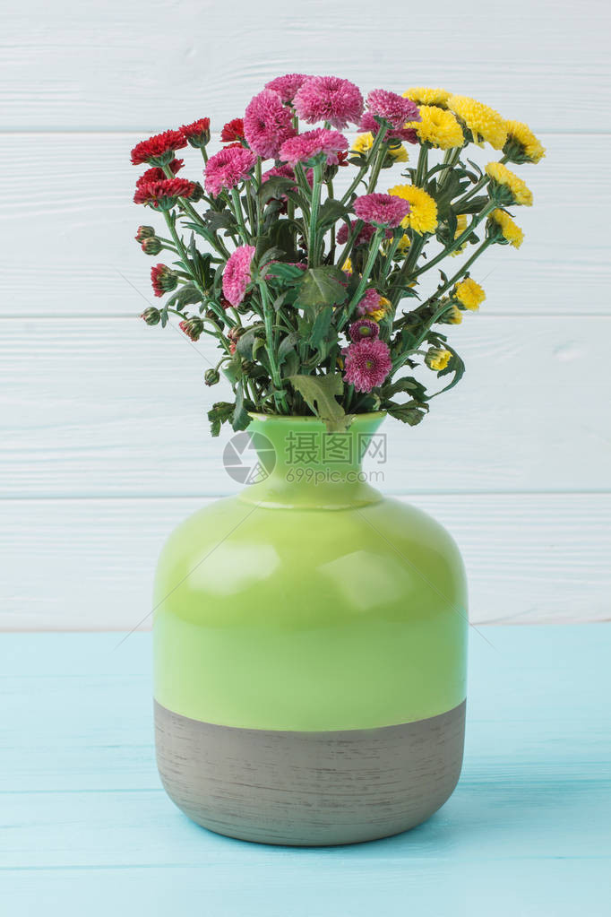 白木底绿色陶瓷花瓶中的菊花图片