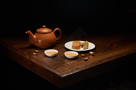 木桌上的茶壶月饼和杯子与黑色隔离图片
