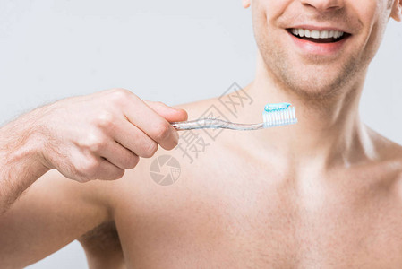 带着牙膏的笑着人用牙膏拿着牙刷在图片