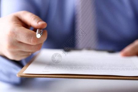 在工作场所特写的银笔相机尖端的西装和领带点的男手臂签署手势阅读协议销售代理银行工作制票据贷款信用抵押投资金融背景图片
