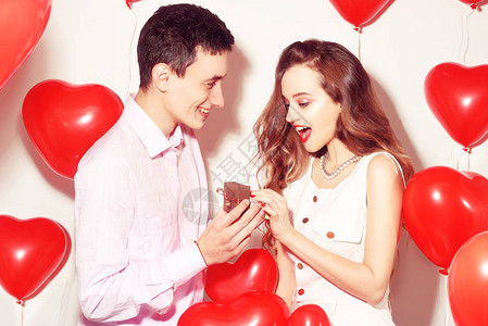 男人做礼物给他可爱的心上人情人的情人节情人节情侣男孩给他的女朋友首饰结婚戒指建议背景红色气球心快背景图片