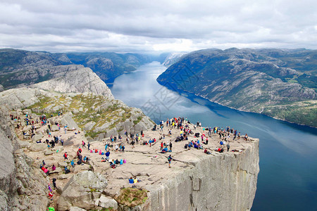 几名徒步旅行者在世界上最壮观的景点之一的讲坛岩Preikestolen山顶欣赏美景位于挪威吕瑟峡湾上方60背景图片