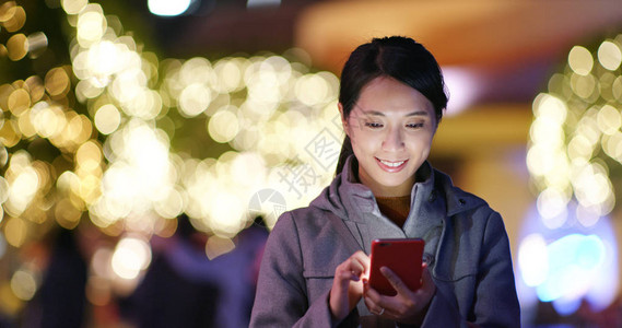 妇女看夜街城市的手机图片