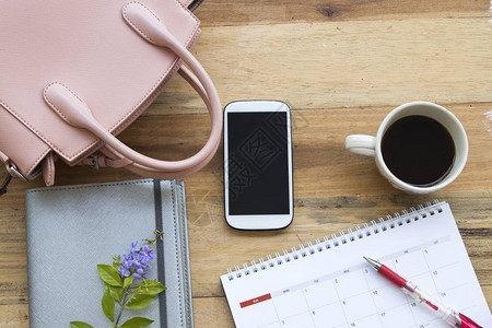 笔记本规划器手机日历和粉红色手提包的生活方式职业女图片