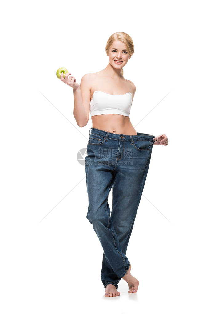 穿着超大牛仔裤的快乐的瘦女孩拿着苹果图片