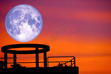 蓝色月亮回到建筑屋顶和日落的天空上图片