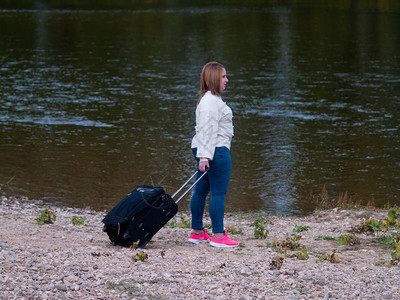 一个孤单悲伤的年轻女人在河边拿着图片