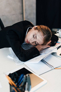 在工作桌睡觉的女商人有选择地以精疲力尽的商图片