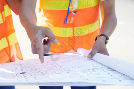 建筑工人的手握检查建筑蓝图的图片