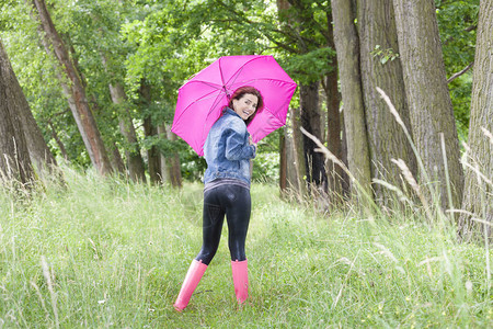 春天大自然中穿着带雨伞的橡胶靴的女人图片