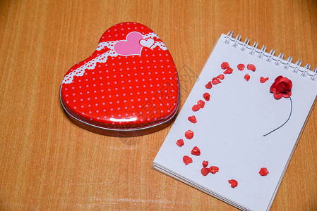 红心形礼物盒和红心在白纸笔记板上图片
