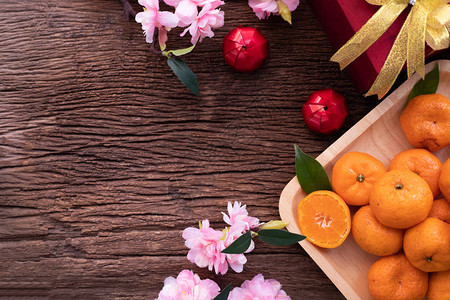 橙子水果粉红樱花和新年成份都放在木板上图片