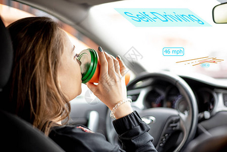 一名年轻女子在自动驾驶模式下乘坐汽车并喝咖啡图片