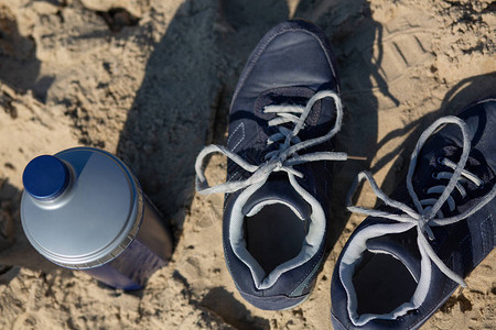 蓝女运动鞋和水瓶贴在沙图片