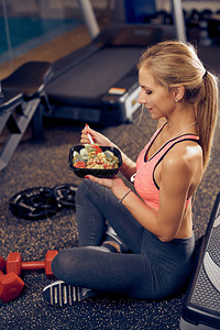 坐在健身房里吃健康食物的女人的侧面图健康的图片