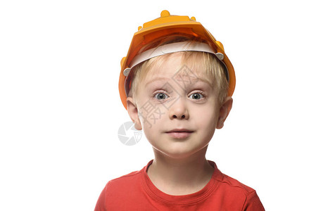 戴着建筑头盔和红色t恤的金发小男孩很惊讶肖像在白图片
