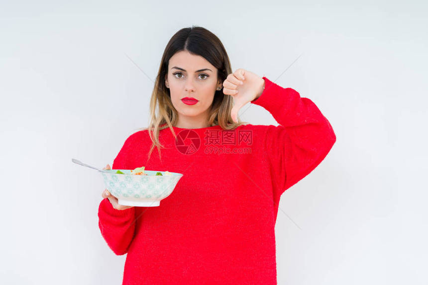 年轻女子在孤立的背景下吃新鲜健康的沙拉图片