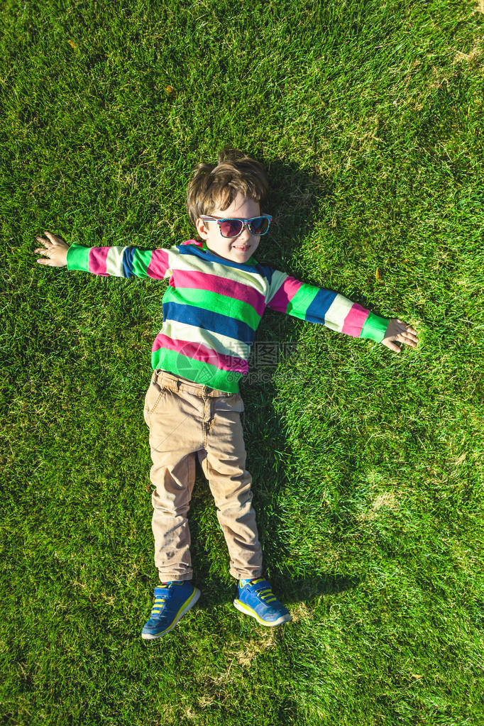 男孩躺在草地上孩子在绿色草坪顶视图上休息孩子在草图片