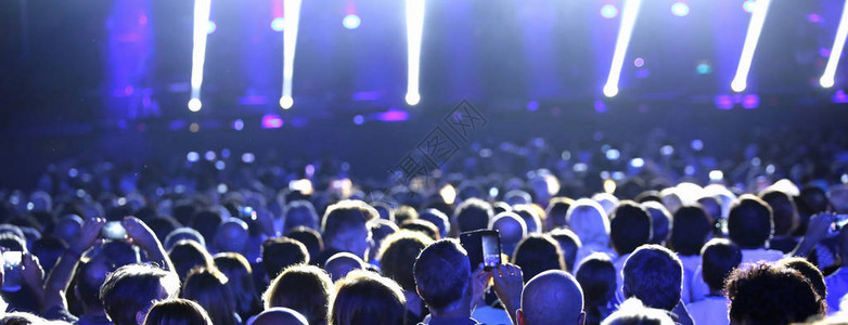 人们在现场音乐会与蓝色的灯光和聚光图片
