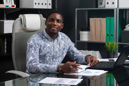 成功的非洲年轻人坐在办公室的办公桌前图片