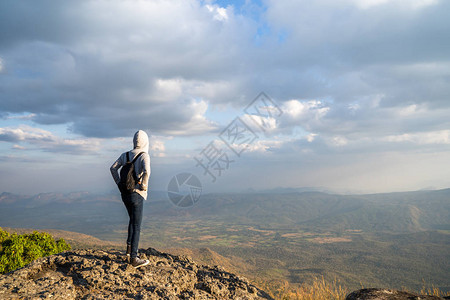 一位站在岩石山上的女人仰望着风景优美的自然景色和图片